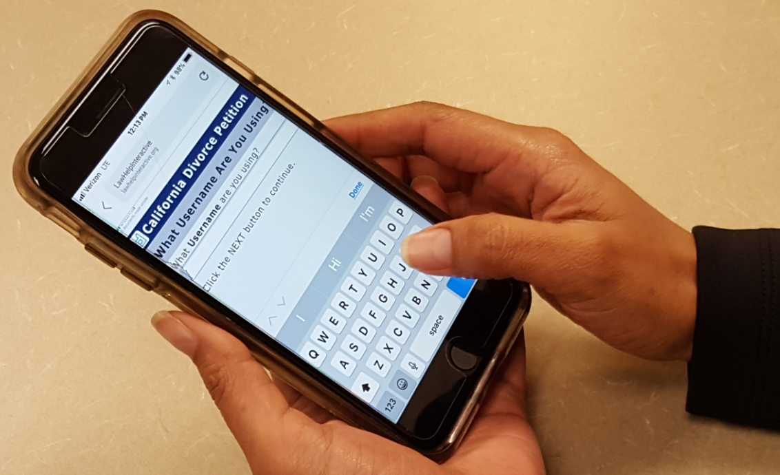 Hands holding a smartphone while typing on an on-screen keyboard; the phone screen shows a “California Divorce Petition” page asking what username the user is using.
